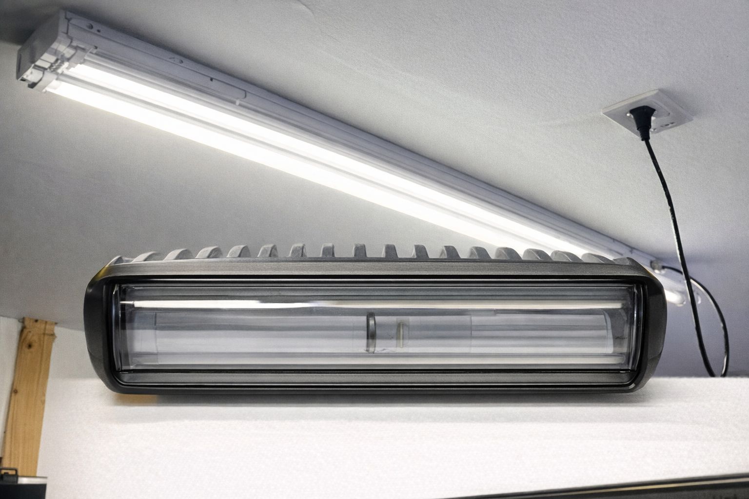 En modern LED-armatur och ett lysrör monterade i ett tak.